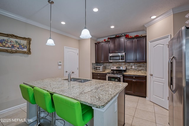 kitchen with appliances with stainless steel finishes, hanging light fixtures, sink, and a center island with sink