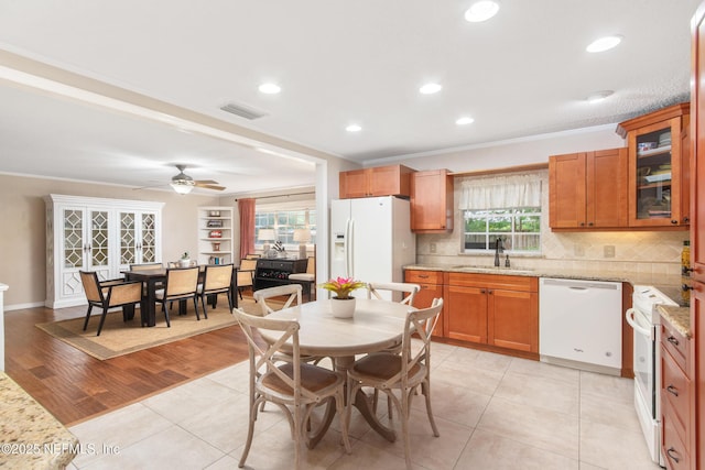 kitchen featuring sink, white appliances, light tile patterned floors, light stone counters, and decorative backsplash