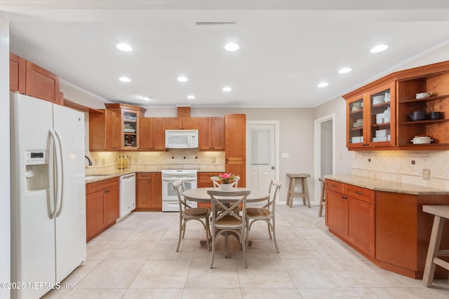 kitchen featuring sink, light tile patterned floors, ornamental molding, white appliances, and light stone countertops