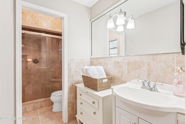 bathroom with tile walls, vanity, a shower with shower door, tile patterned floors, and toilet