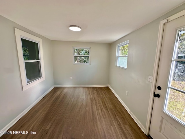 spare room with a healthy amount of sunlight and dark hardwood / wood-style floors