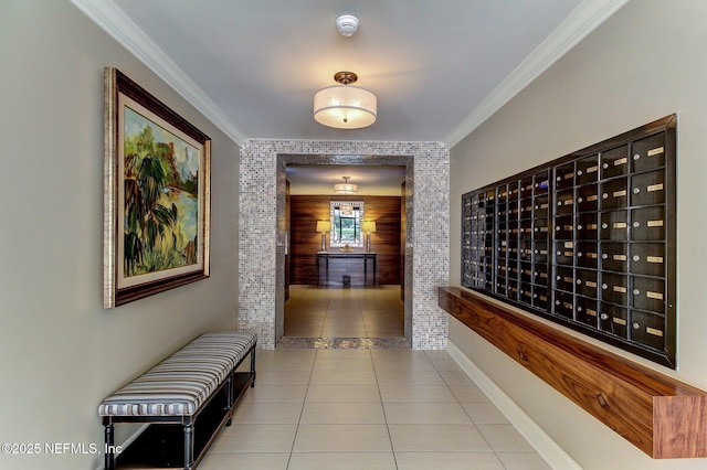 hall with crown molding, wooden walls, light tile patterned floors, and a mail area