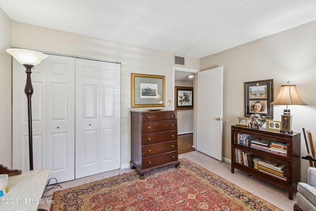 bedroom featuring light colored carpet, a closet, and a textured ceiling