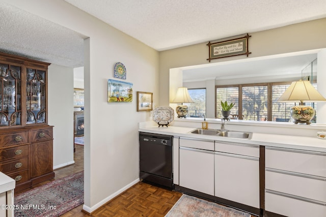 kitchen featuring sink, dishwasher, white cabinetry, dark parquet floors, and a textured ceiling