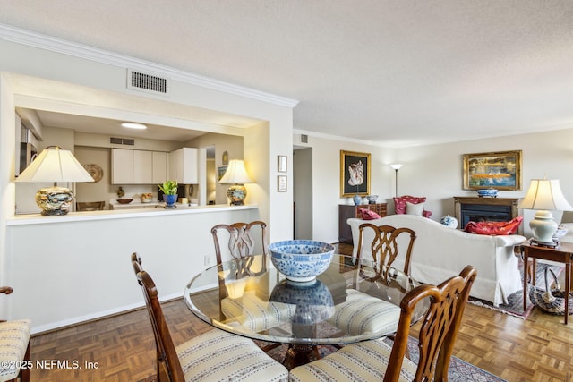 dining room with parquet flooring, ornamental molding, and a textured ceiling