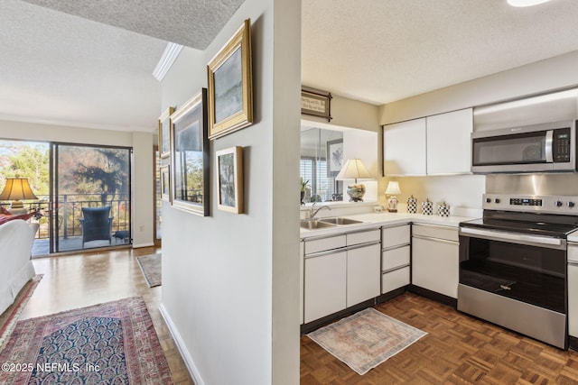 kitchen with appliances with stainless steel finishes, sink, a textured ceiling, and white cabinets