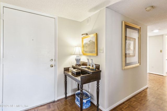 entrance foyer featuring dark parquet flooring and a textured ceiling