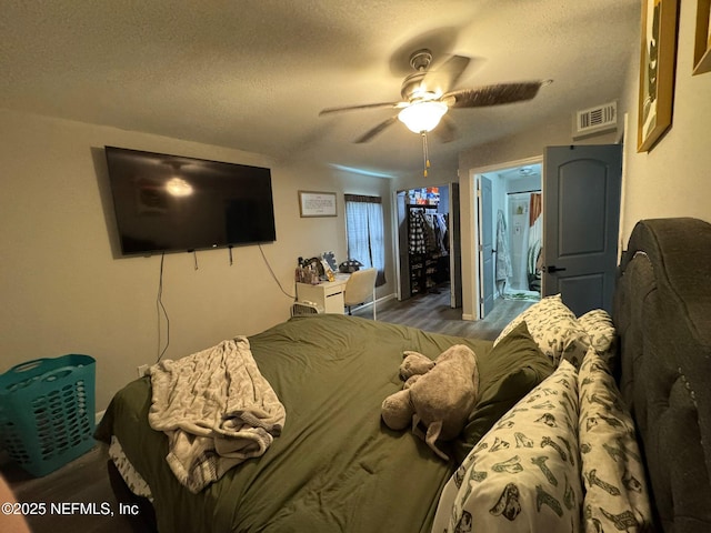 bedroom featuring ceiling fan, hardwood / wood-style floors, and a textured ceiling