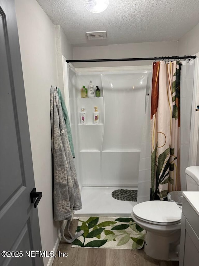 bathroom featuring a shower with shower curtain, vanity, wood-type flooring, a textured ceiling, and toilet