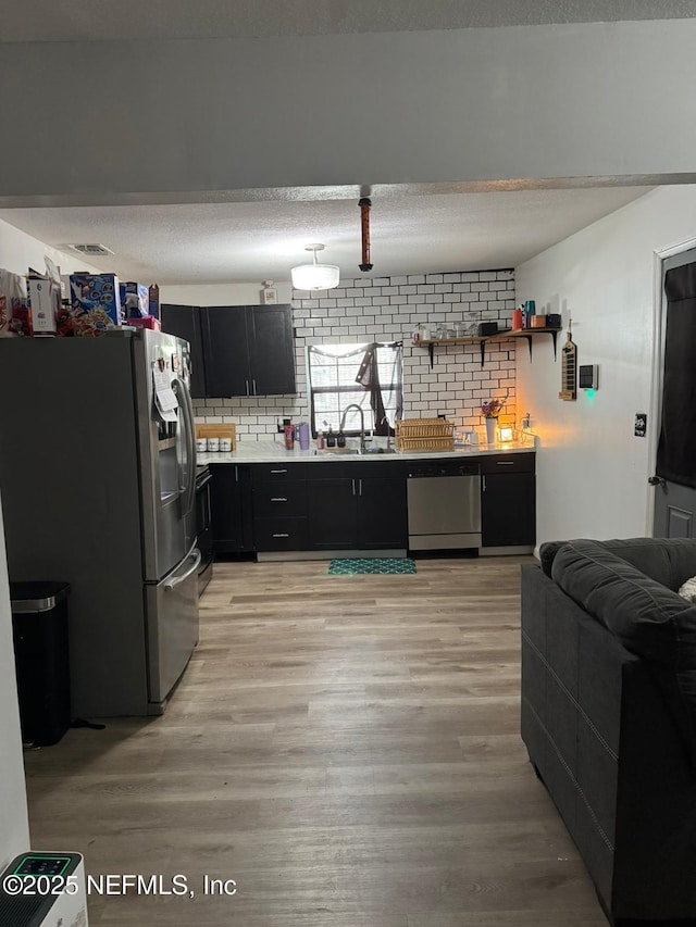 kitchen with tasteful backsplash, sink, stainless steel appliances, and light hardwood / wood-style floors