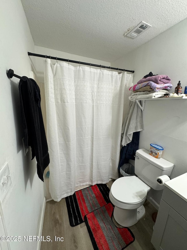 bathroom featuring wood-type flooring, curtained shower, vanity, and toilet