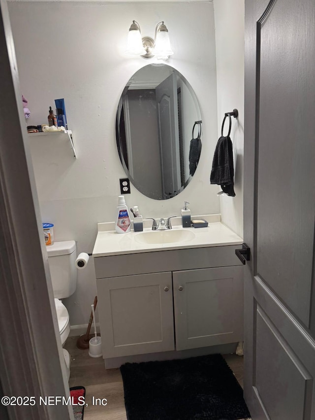 bathroom with hardwood / wood-style flooring, vanity, and toilet