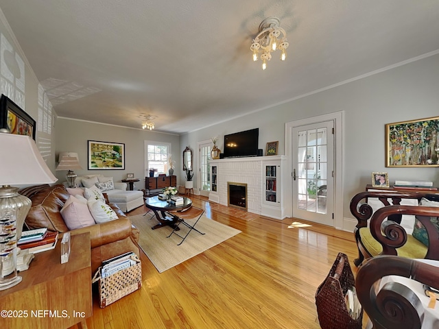 living room with crown molding, a brick fireplace, plenty of natural light, and light wood-type flooring