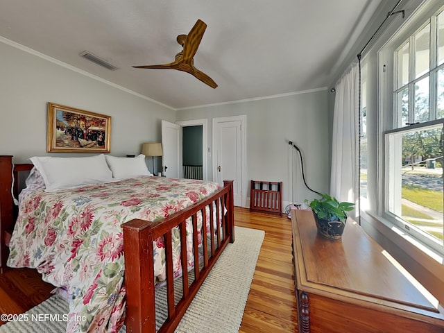 bedroom featuring crown molding, ceiling fan, multiple windows, and light hardwood / wood-style flooring