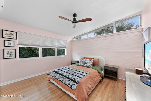 bedroom with lofted ceiling, multiple windows, and light wood-type flooring