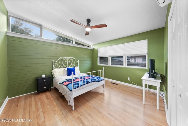 bedroom featuring ceiling fan, a textured ceiling, vaulted ceiling, and wood-type flooring