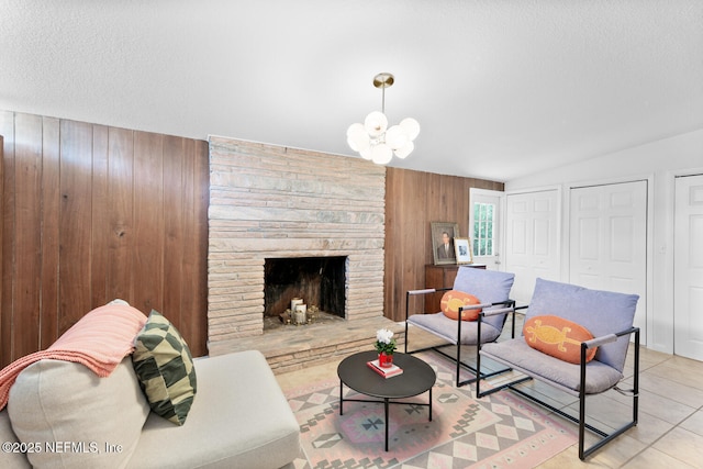 tiled living room featuring lofted ceiling, a notable chandelier, a textured ceiling, a stone fireplace, and wood walls