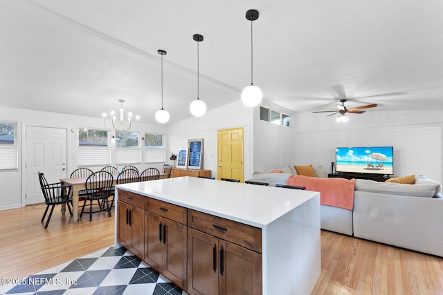 kitchen with hanging light fixtures, a center island, ceiling fan with notable chandelier, and light hardwood / wood-style flooring