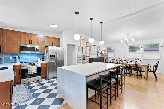 kitchen featuring appliances with stainless steel finishes, a center island, hanging light fixtures, and a breakfast bar area