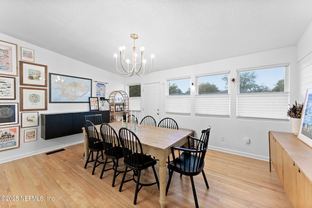 dining area featuring a notable chandelier, light hardwood / wood-style flooring, and a textured ceiling