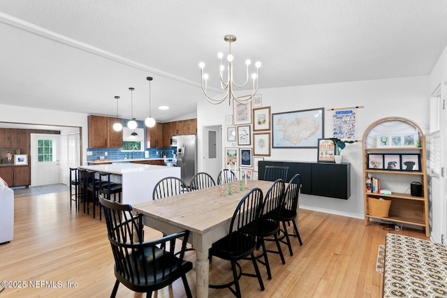 dining space featuring sink, vaulted ceiling, light hardwood / wood-style flooring, and a notable chandelier