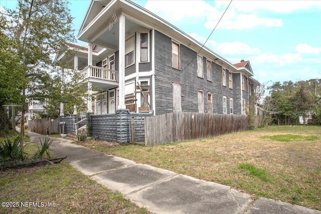 view of side of home with a balcony and a lawn