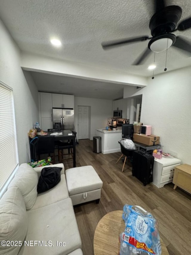 living room featuring ceiling fan, a textured ceiling, and dark hardwood / wood-style flooring