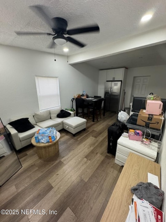 living room with ceiling fan, wood-type flooring, and a textured ceiling