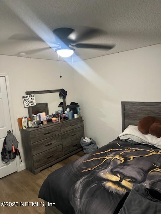 bedroom featuring ceiling fan, wood-type flooring, and a textured ceiling