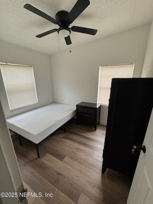 bedroom with ceiling fan, hardwood / wood-style flooring, and a textured ceiling