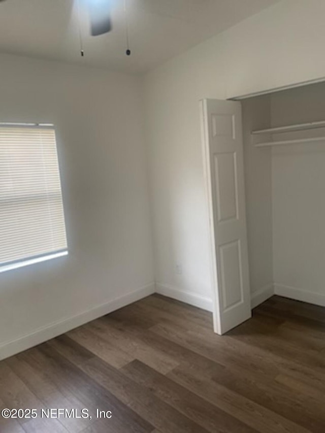 unfurnished bedroom featuring dark hardwood / wood-style floors, ceiling fan, and a closet