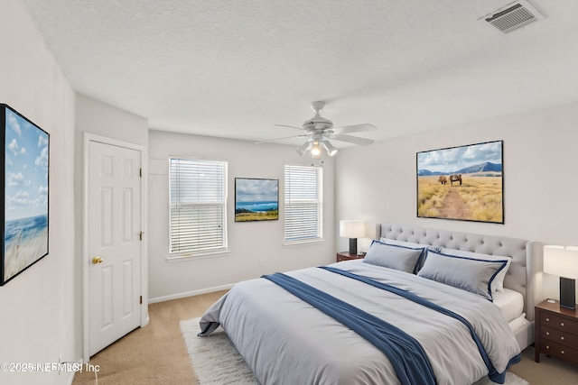 carpeted bedroom with ceiling fan and a textured ceiling