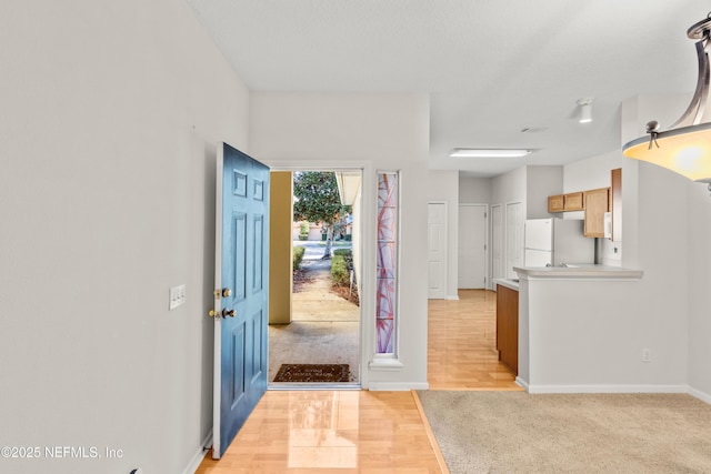 foyer entrance with a textured ceiling and light hardwood / wood-style flooring