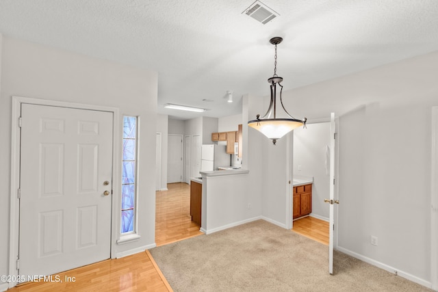 foyer with a textured ceiling and light hardwood / wood-style floors