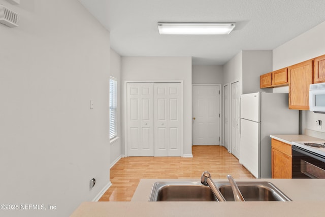 kitchen with white appliances, light hardwood / wood-style floors, and sink