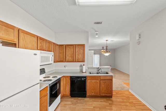 kitchen with sink, white appliances, light hardwood / wood-style flooring, hanging light fixtures, and a textured ceiling