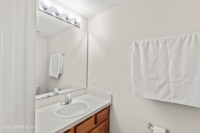 bathroom with vanity, toilet, and a textured ceiling