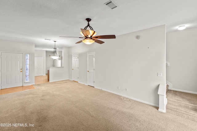 unfurnished living room featuring ceiling fan, carpet flooring, and a textured ceiling