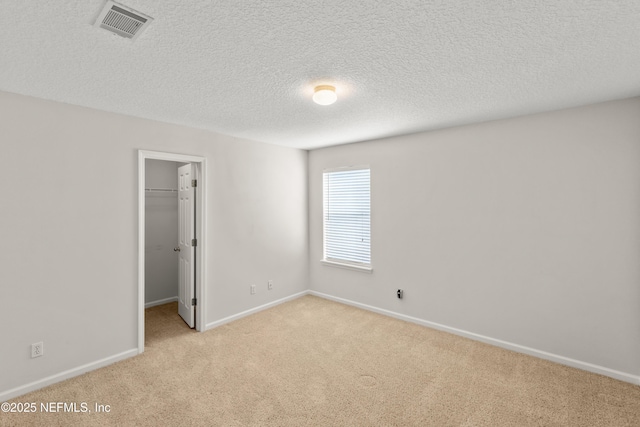 empty room featuring light colored carpet and a textured ceiling