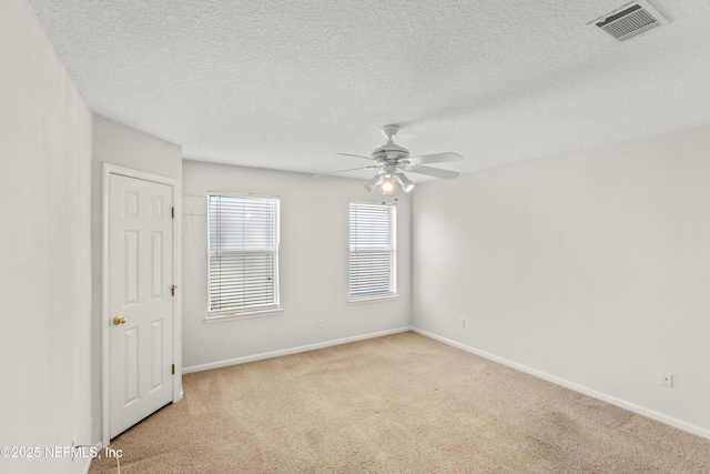 spare room featuring light colored carpet, a textured ceiling, and ceiling fan