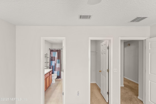 corridor with light carpet and a textured ceiling