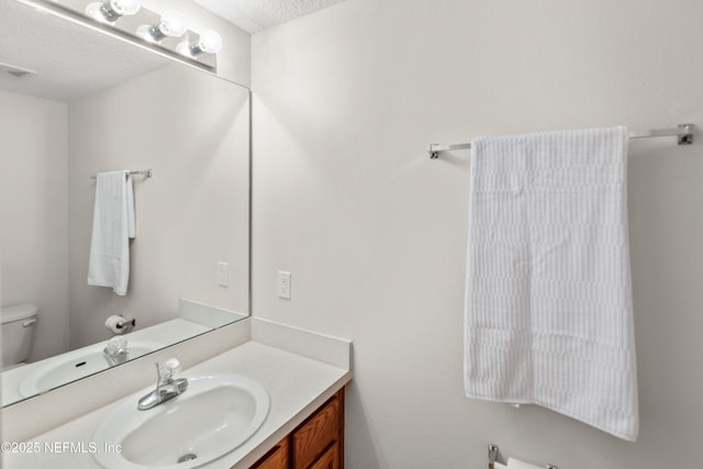 bathroom featuring vanity, toilet, and a textured ceiling