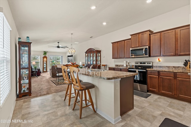 kitchen featuring appliances with stainless steel finishes, pendant lighting, an island with sink, sink, and a kitchen bar