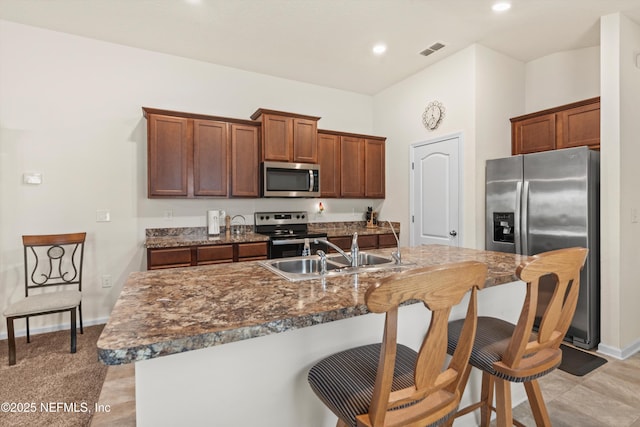 kitchen featuring stainless steel appliances, a breakfast bar, sink, and a center island with sink