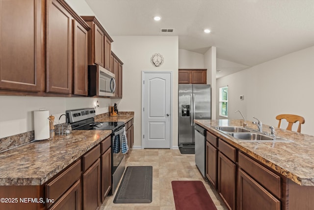 kitchen featuring vaulted ceiling, an island with sink, appliances with stainless steel finishes, and sink