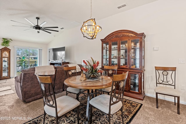 carpeted dining space featuring ceiling fan with notable chandelier and vaulted ceiling