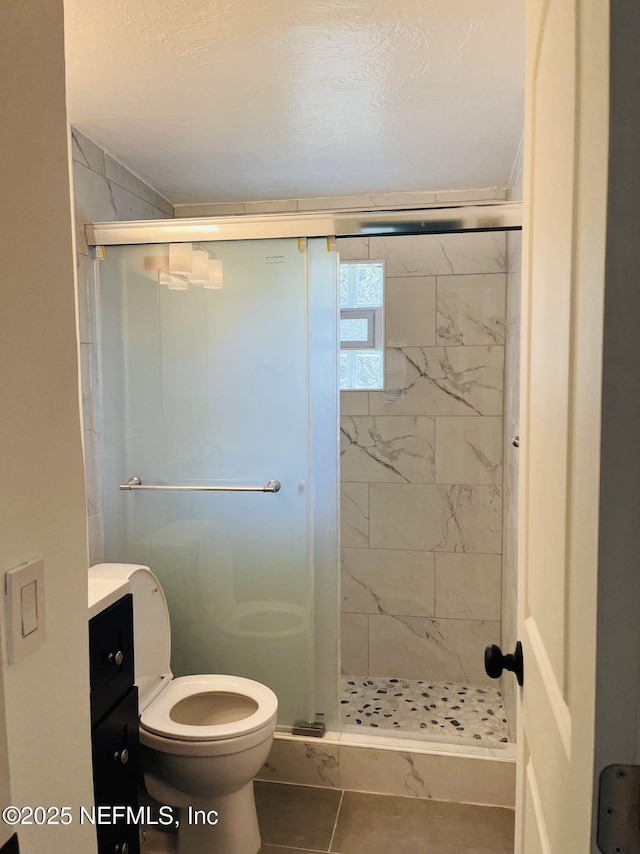 bathroom with vanity, tile patterned flooring, a shower with shower door, and toilet