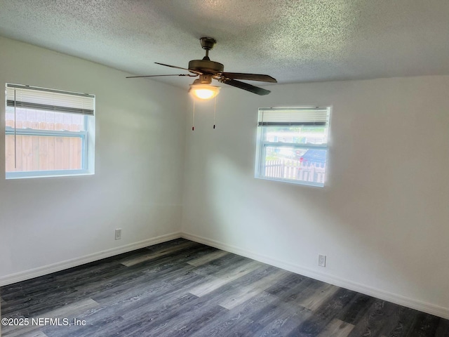 empty room with dark hardwood / wood-style flooring, plenty of natural light, and a textured ceiling