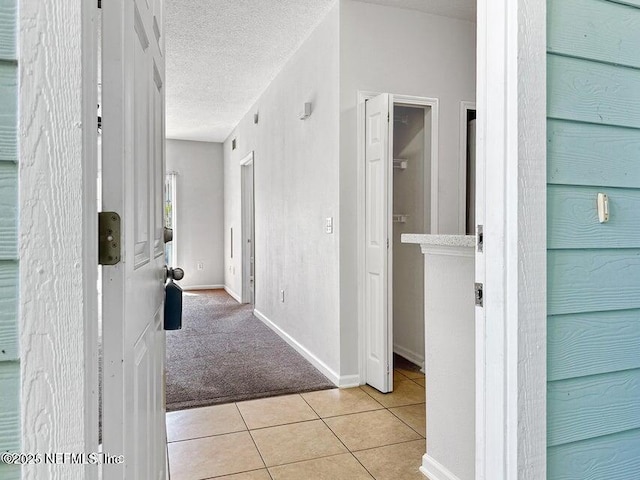 hallway with light tile patterned flooring and a textured ceiling