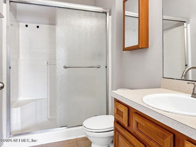 bathroom featuring a shower with door, vanity, tile patterned floors, and toilet